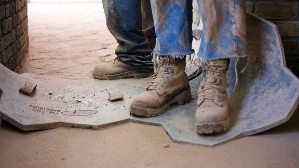 Concreter applying a stamped pattern to fresh concrete surface
